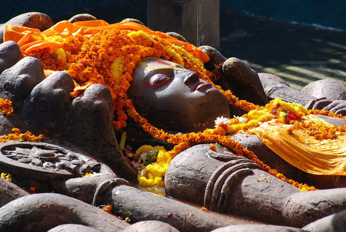Kathmandu Valley 1 Budhanikantha 3 Sleeping Vishnu Head Close Up Budhanilkantha Narayan (Sleeping Vishnu) lies peacefully on the coils of the multi-headed snake Ananta. The snake�s 11 hooded heads rise protectively around Narayan�s head. Vishnu�s four hands hold the four symbols of Vishnu: chakra disk(representing the mind), a conch shell (the four elements), a mace (primeval knowledge), and a lotus seed (the moving universe).
